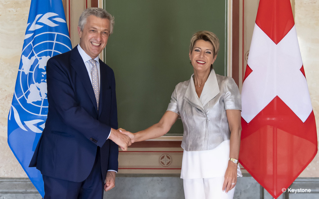 L’alto commissario Filippo Grandi e la consigliera federale Karin Keller-Sutter si stringono la mano davanti alle bandiere dell’ONU e della Svizzera